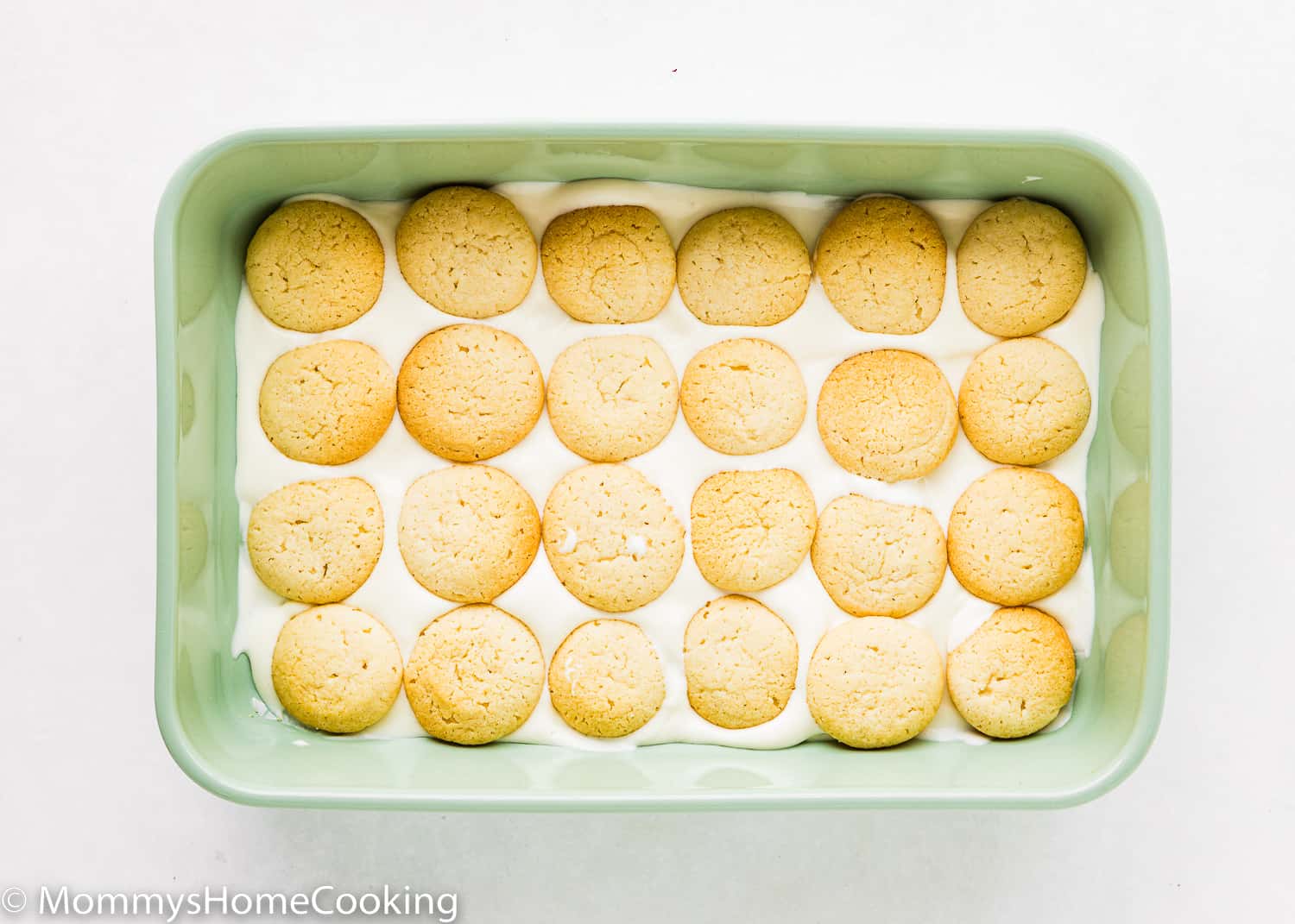 A rectangular green dish with pudding on the bottom and egg-free vanilla wafers.