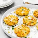 egg-free corn fritter on a plate sprinkled with cheese and chopped cilantro.