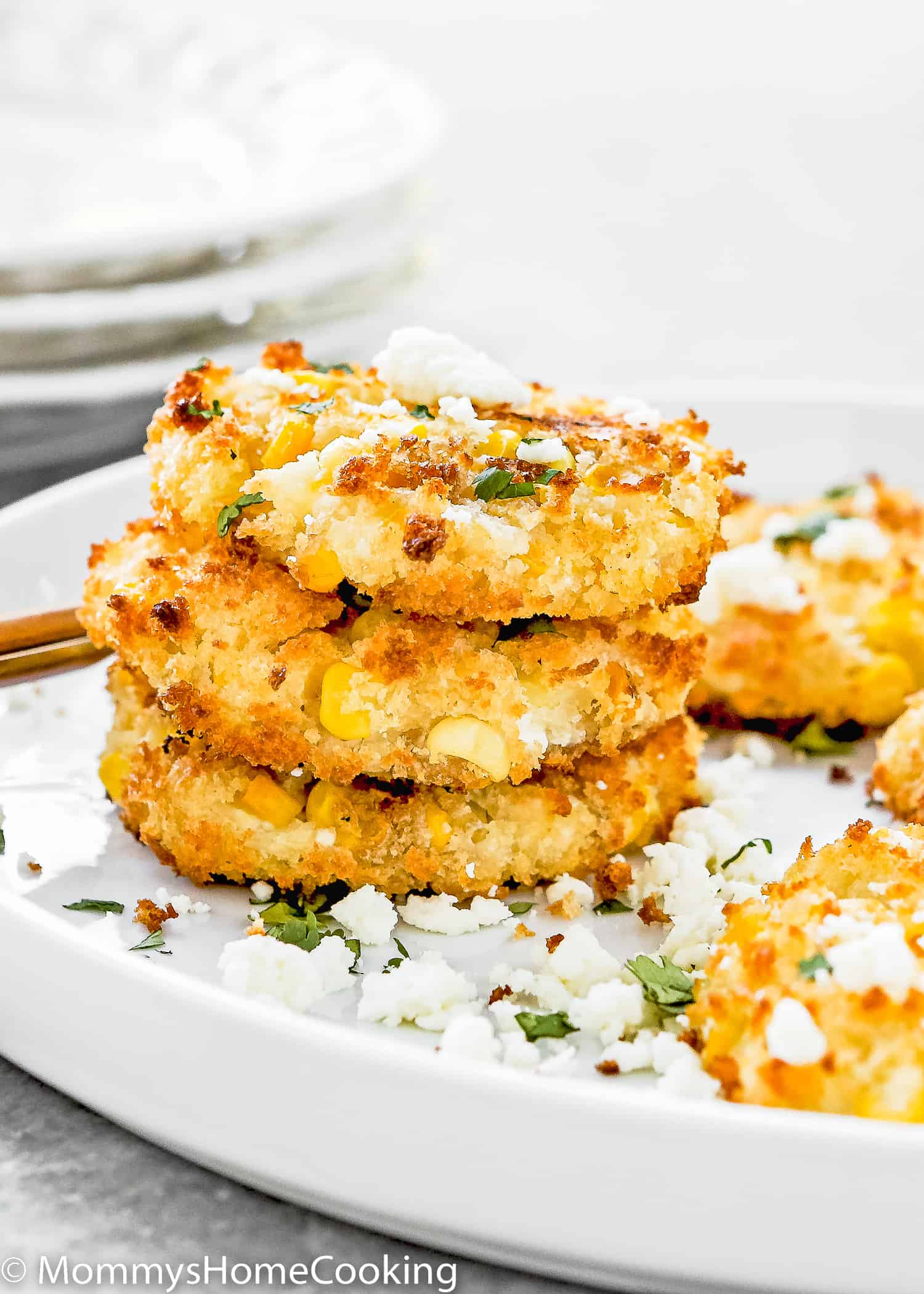 three egg-free corn fritter in a plate with cheese and chopped cilantro.