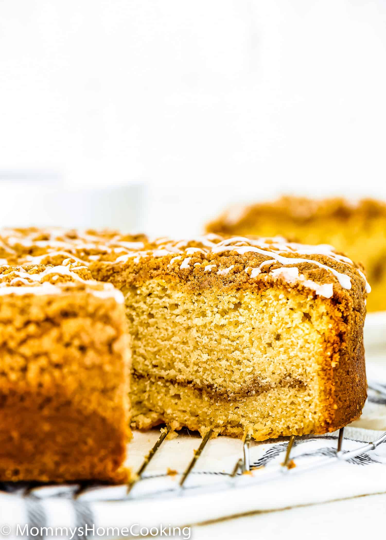 A sliced Eggless Coffee Cake with streusel and glaze on top over a cooling rack.