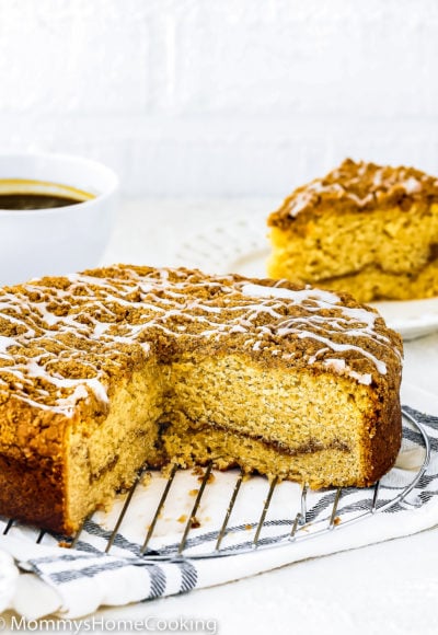 A sliced Eggless Coffee Cake over a cooling rack with a slice on the background.