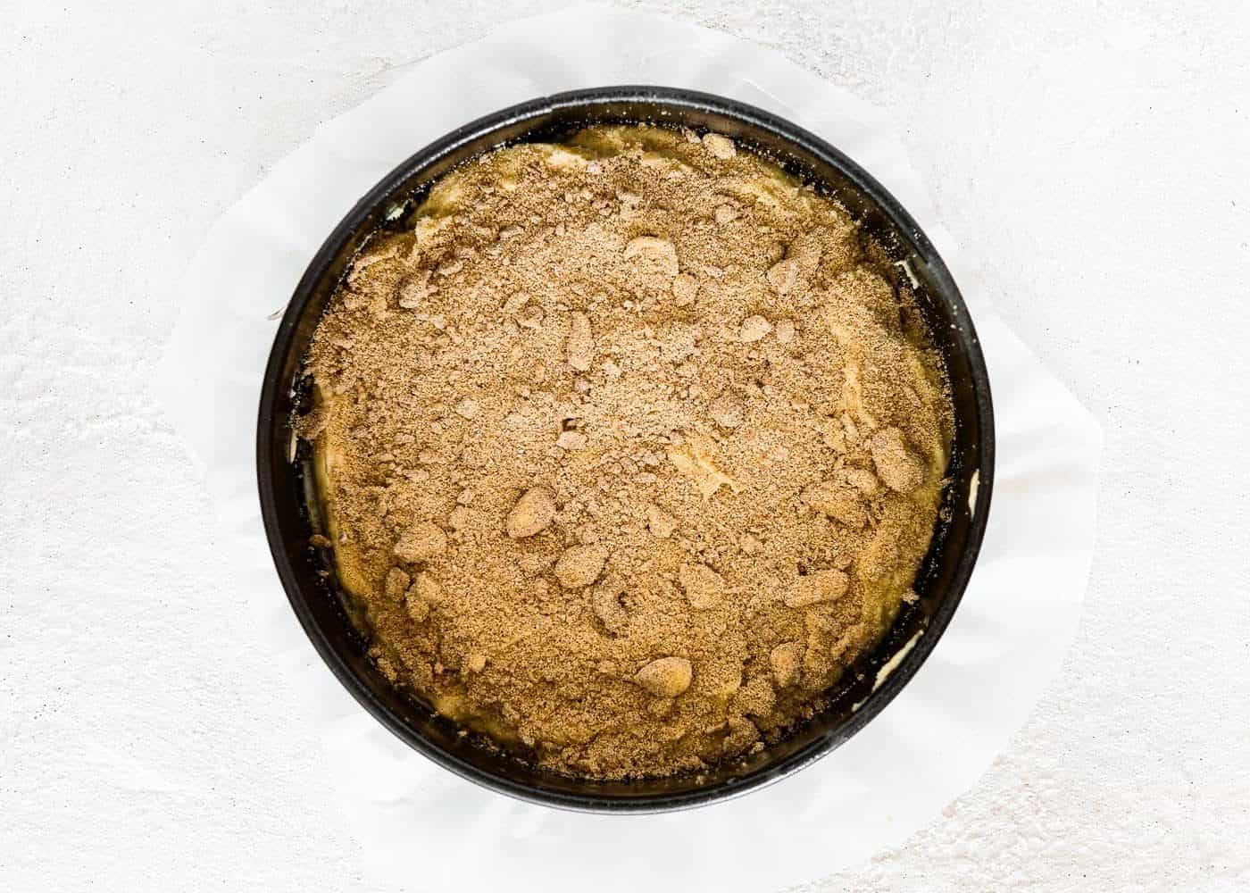 eggless coffee cake batter in a springform pan with streusel in top. 
