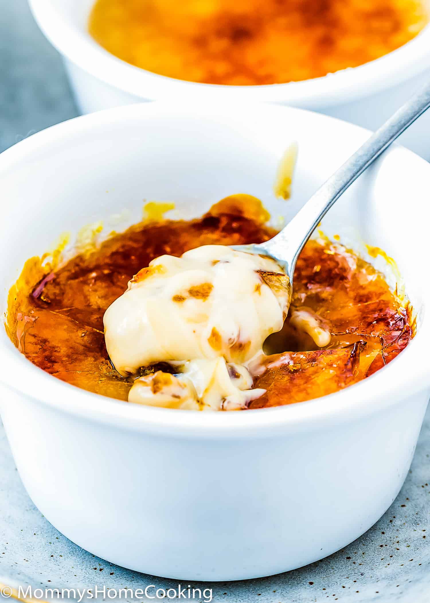 a small spoon with egg-free creme brulee with a sugar caramelized top.