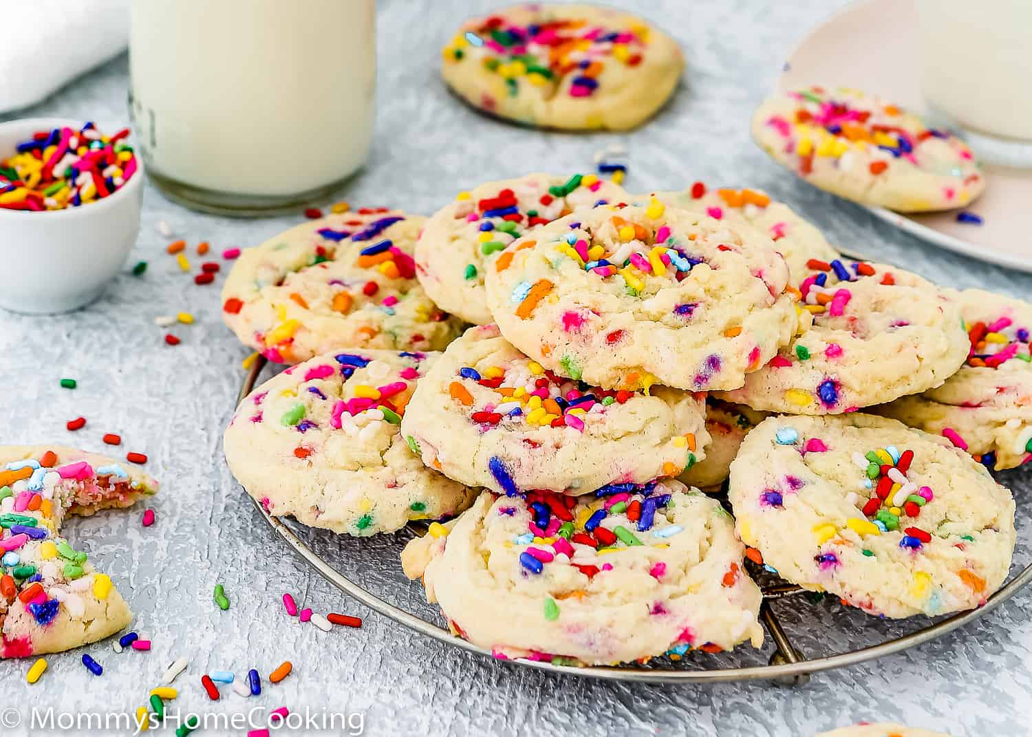 eggless Funfetti cookies on a cooling rack with sprinkles and more cookies around it.