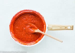 reduced Strawberry purée in a skillet with a wooden spoon.