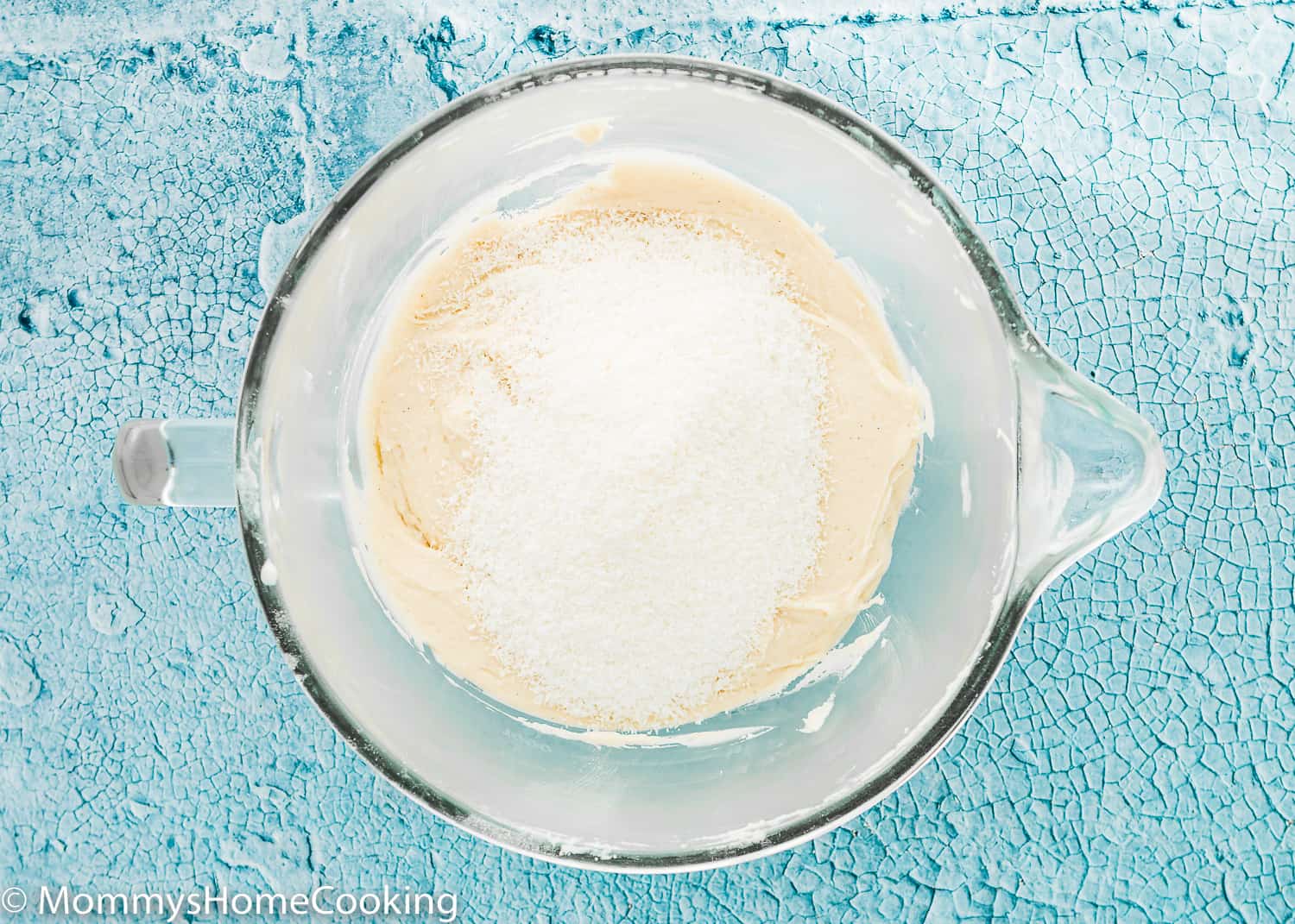 eggless Coconut Cake batter in a stand mixer bowl with shredded coconut on top.