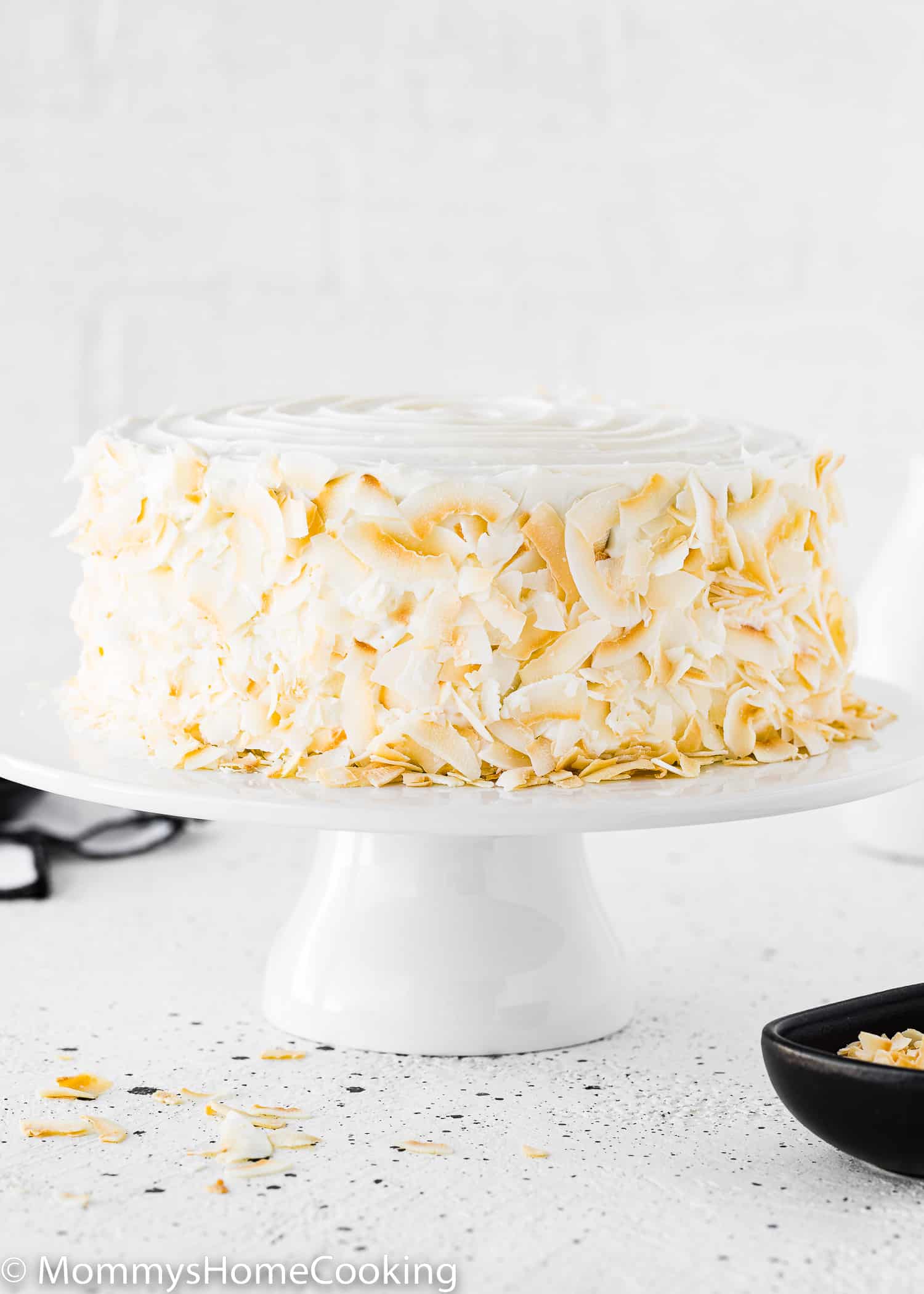 An Eggless Coconut Cake on a cake stand.