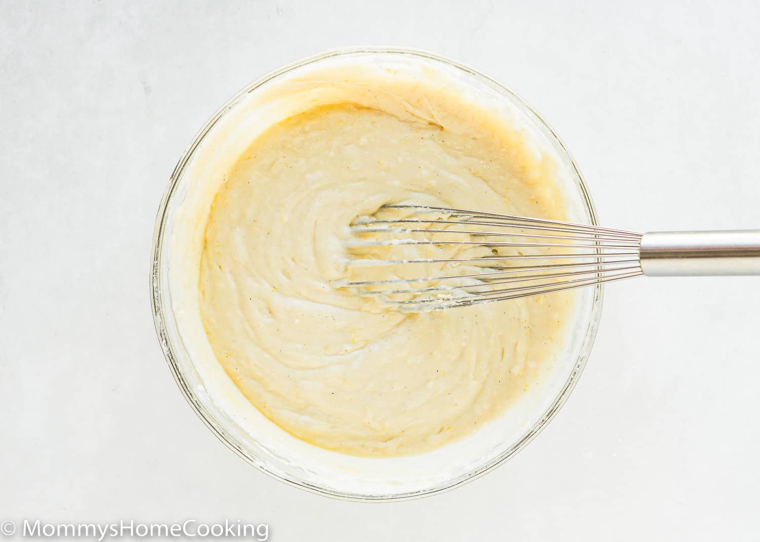 Eggless Lemon Muffins batter in a bowl with a whisk.