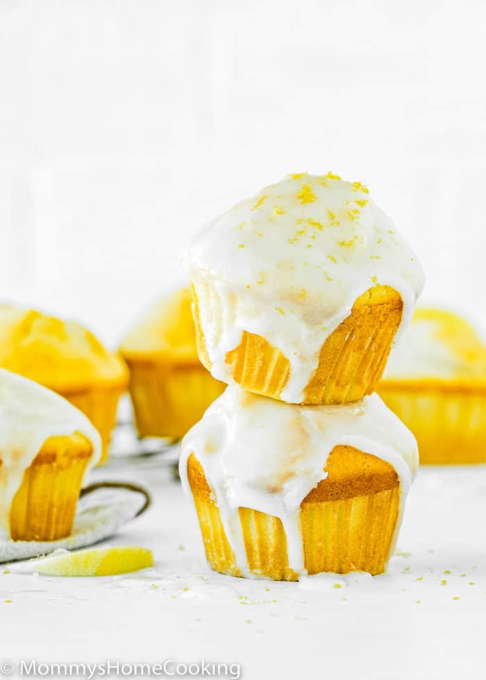 a stack of two Eggless Lemon Muffins with glaze, with more egg-free Muffins around it.
