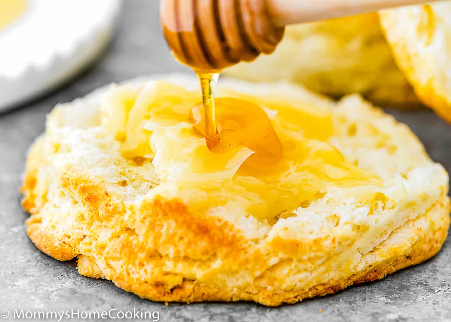 honey being poured over a egg-free homemade biscuit with butter