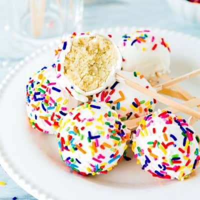 homemade egg-free cake pops on a plate with a bowl of sprinkles on the background.