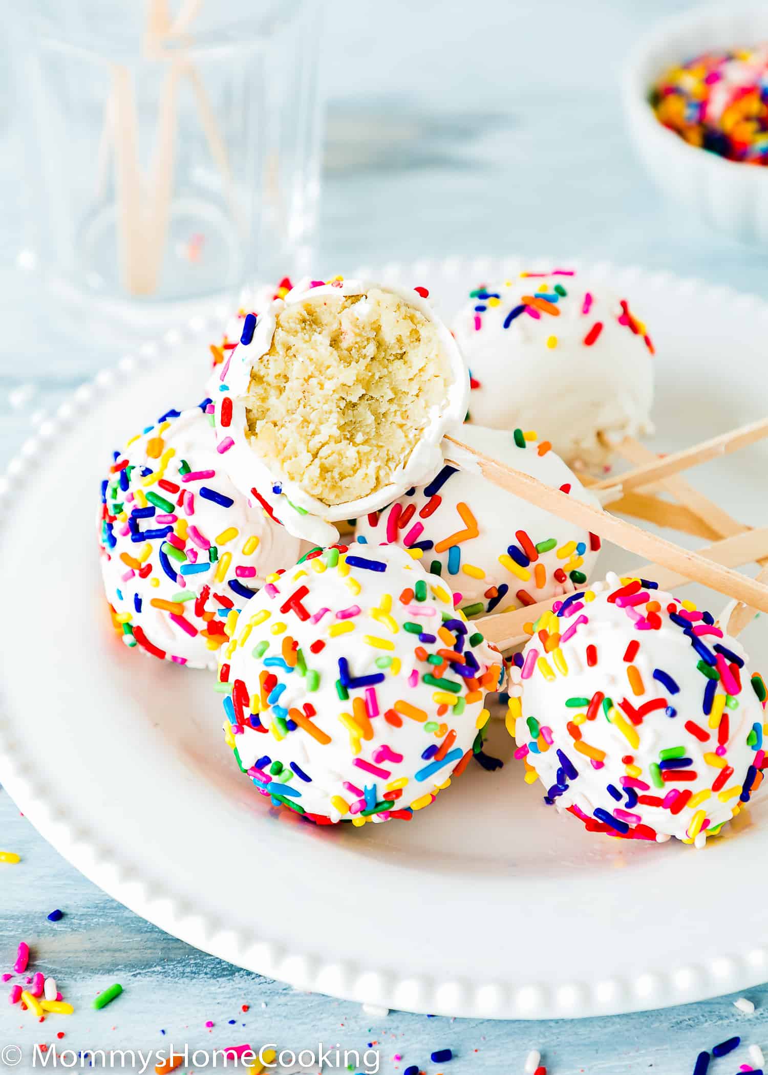 homemade egg-free cake pops on a plate with a bowl of sprinkles on the background.