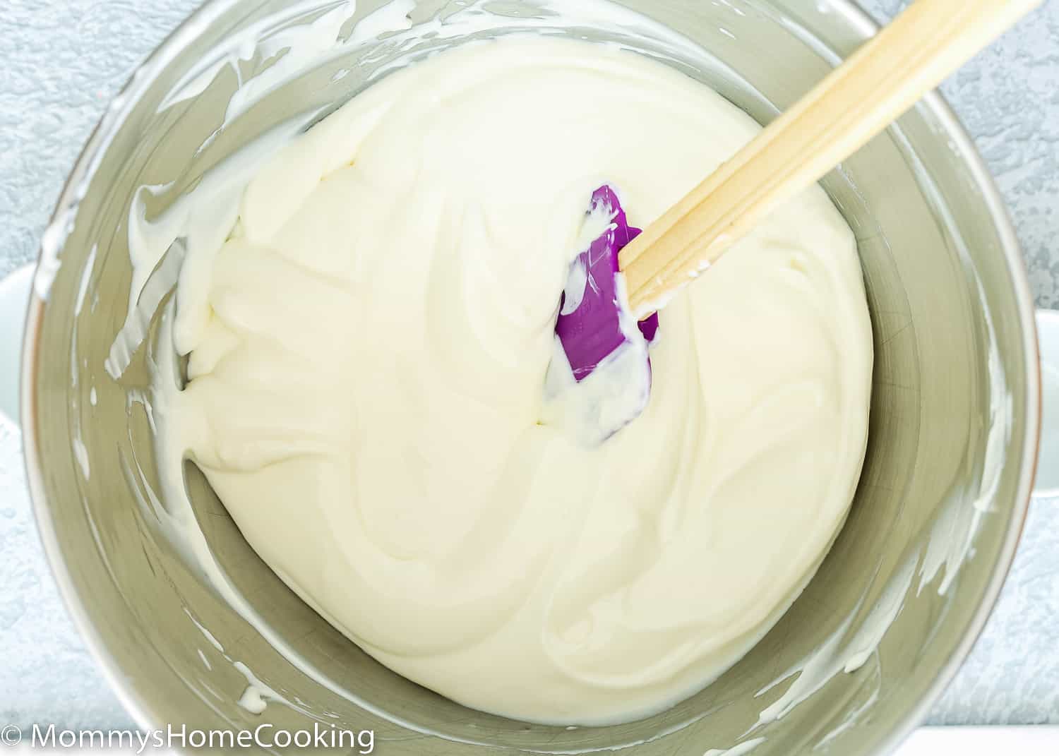 egg-free cheesecake batter in a stand mixer bowl with a spatula.