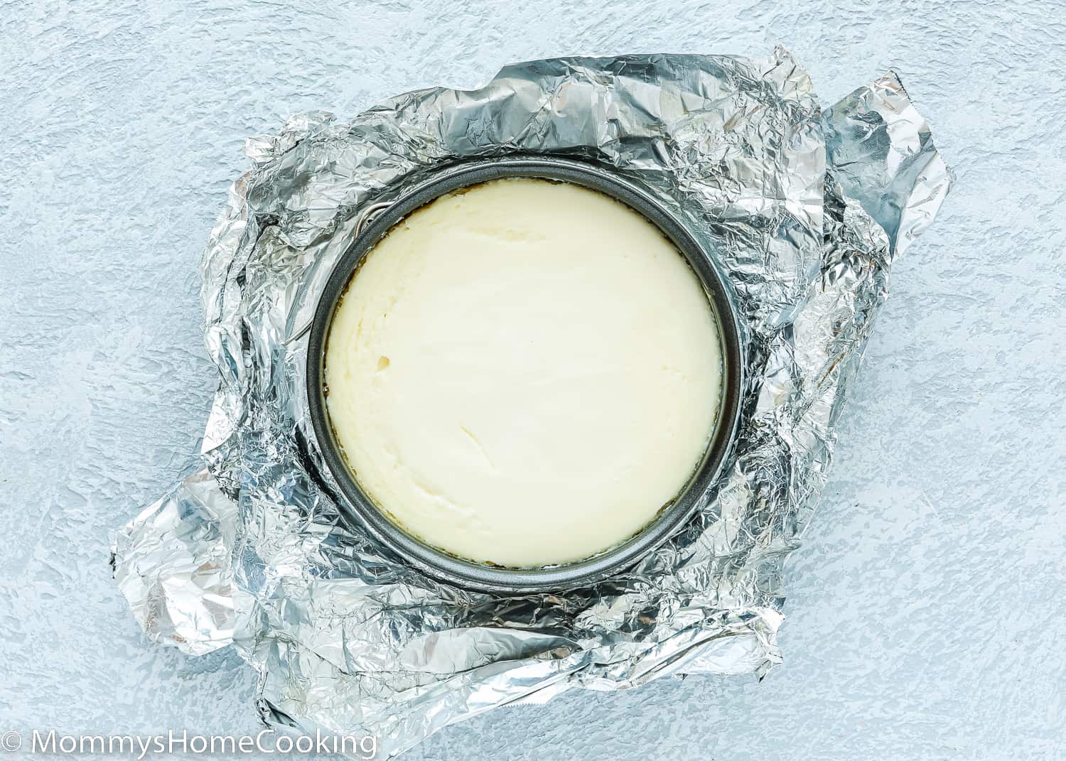 an egg-free instant poto cheesecake in a springform pan over a piece of foil.