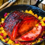 a chipotle glazed ham in a cash iron skillet with pineapple and cranberries.