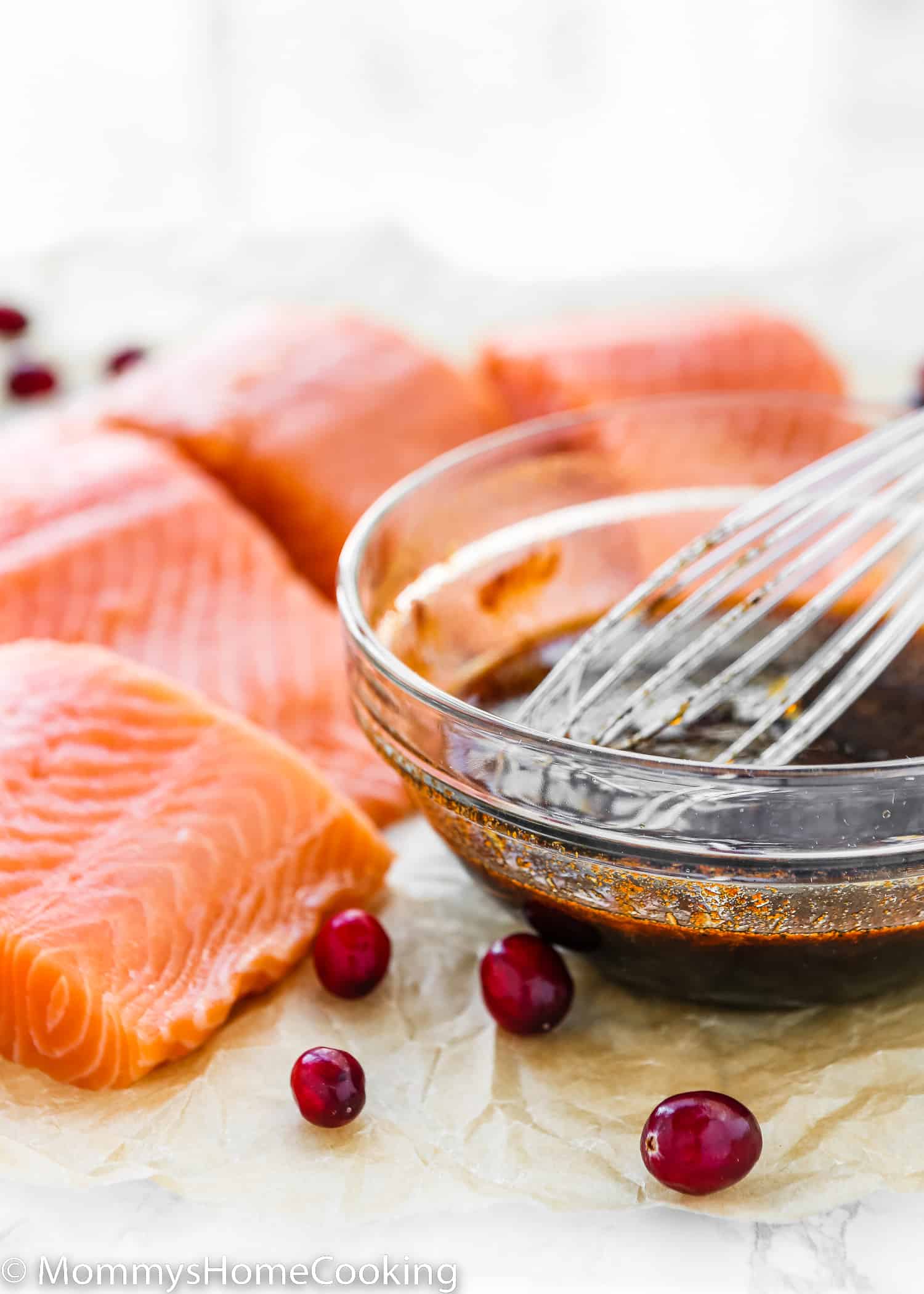 Uncooked salmon fillets next to a bowl with cranberry honey marinade.