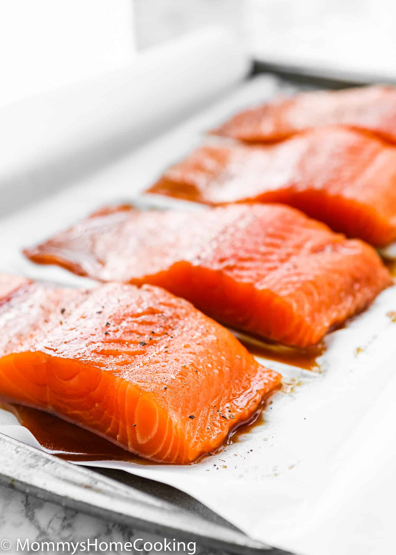Uncooked salmon fillets over a baking sheet.