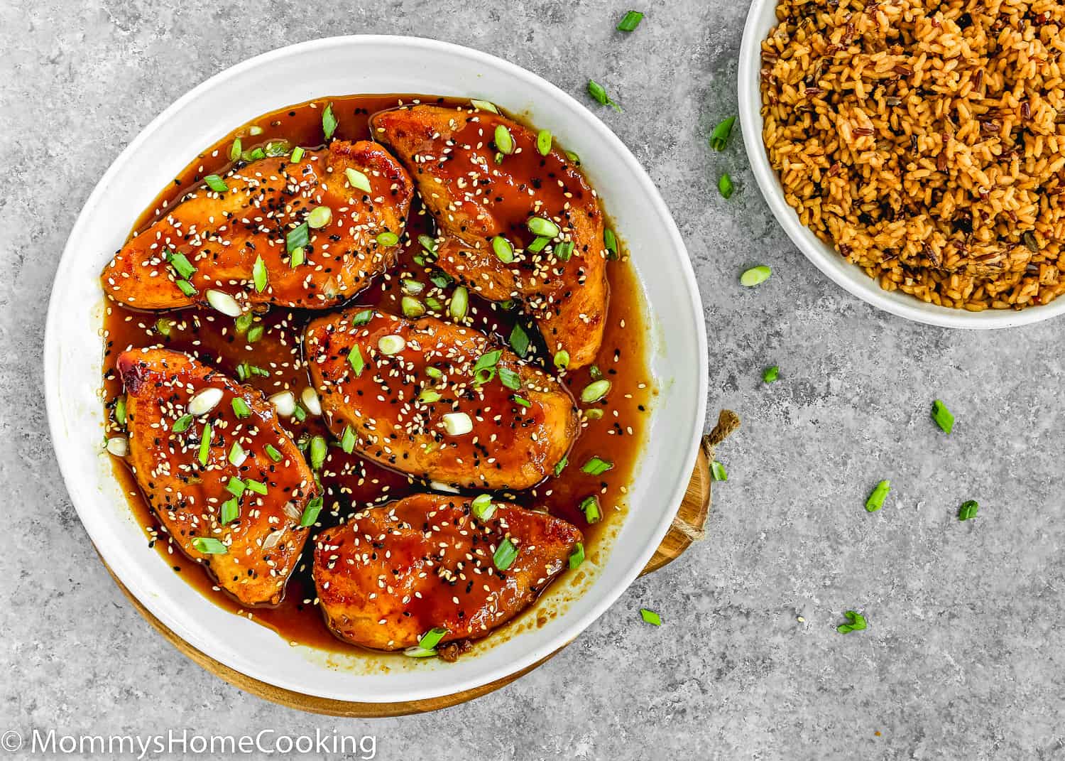 Asian-Style sticky Chicken Breasts in a white skillet with a plate with rice on the side.