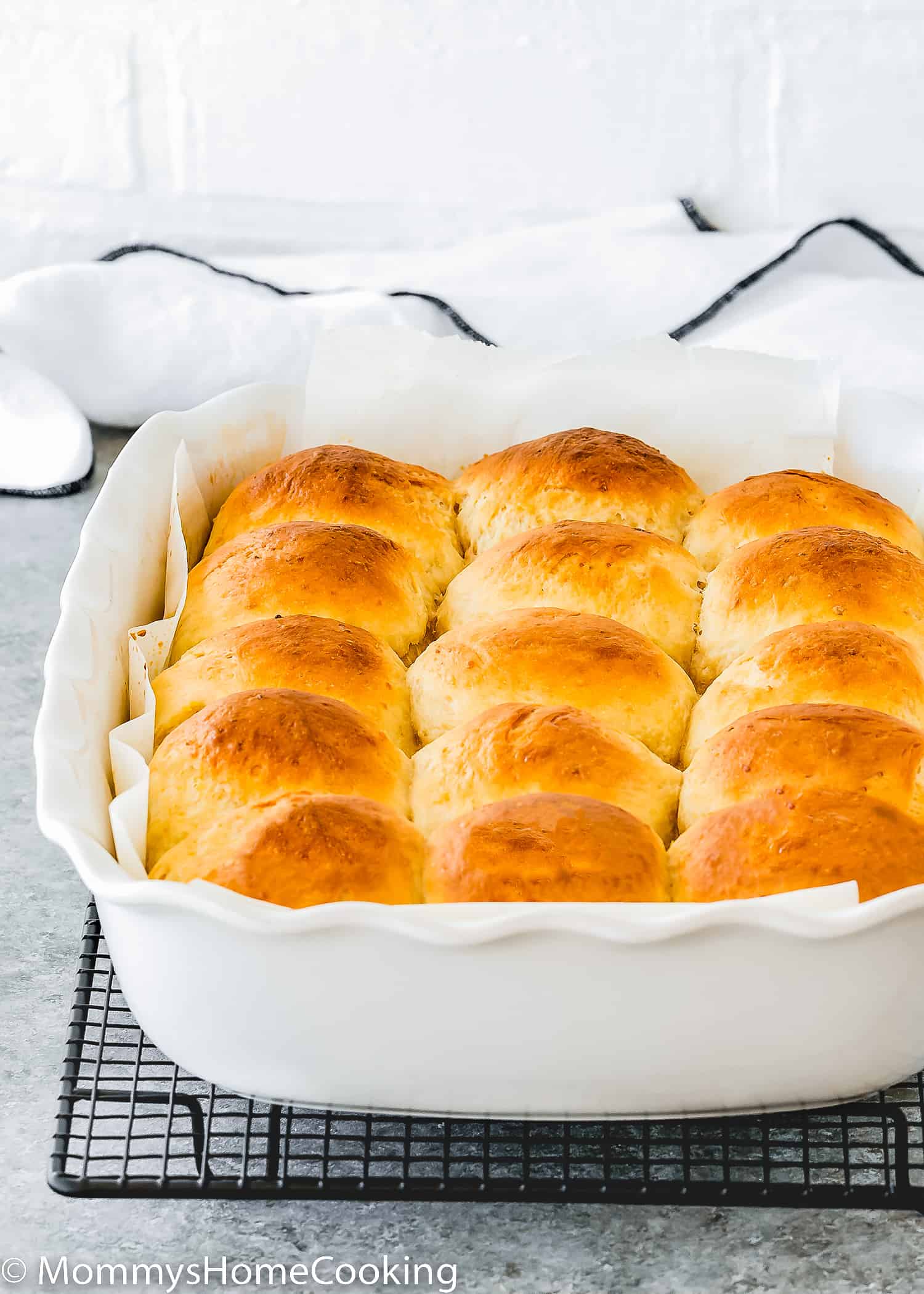 egg-free homemade hawaiian rolls in a baking pan over a cooling rack.