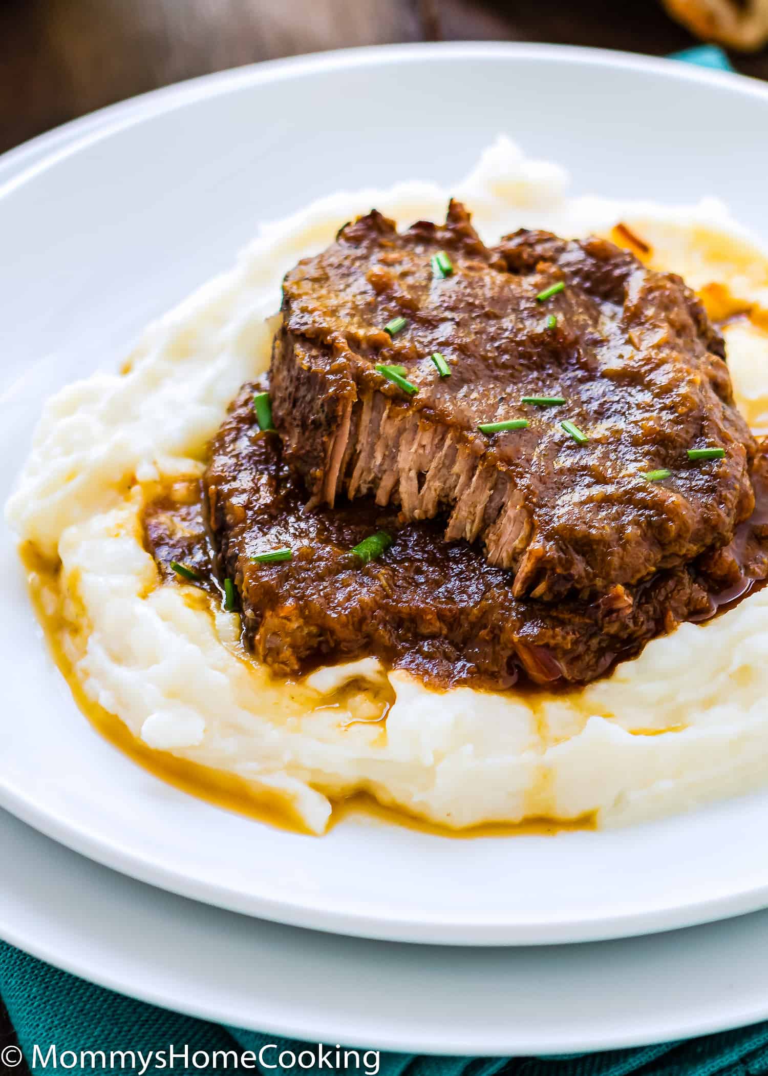 two slices of Venezuelan Asado Negro with sauce over mashed potatoes.