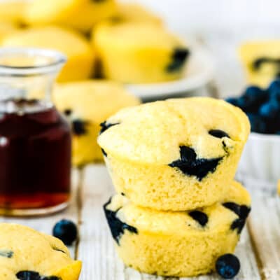 two Eggless Blueberry Pancake Muffins stack with maple syrup on the side.