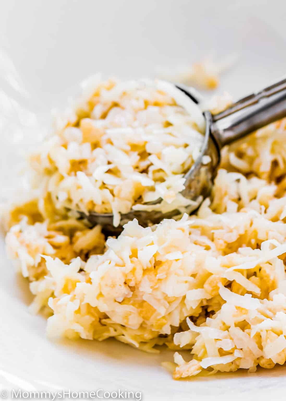 Eggless Coconut Macaroon mixture in a bowl with a ice cream scoop.