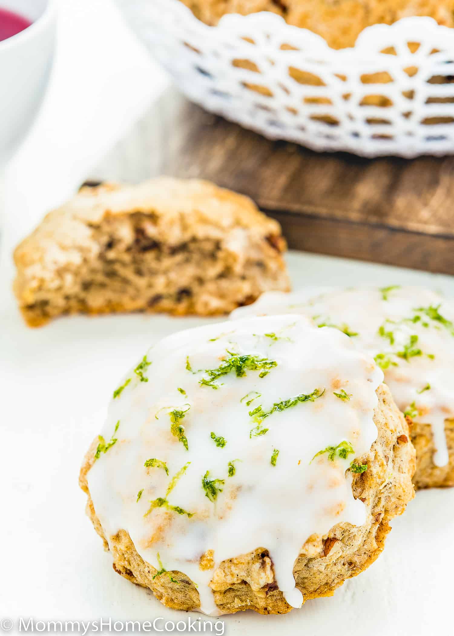 Eggless Gingerbread Scones with glaze and lime zest over a white surface.