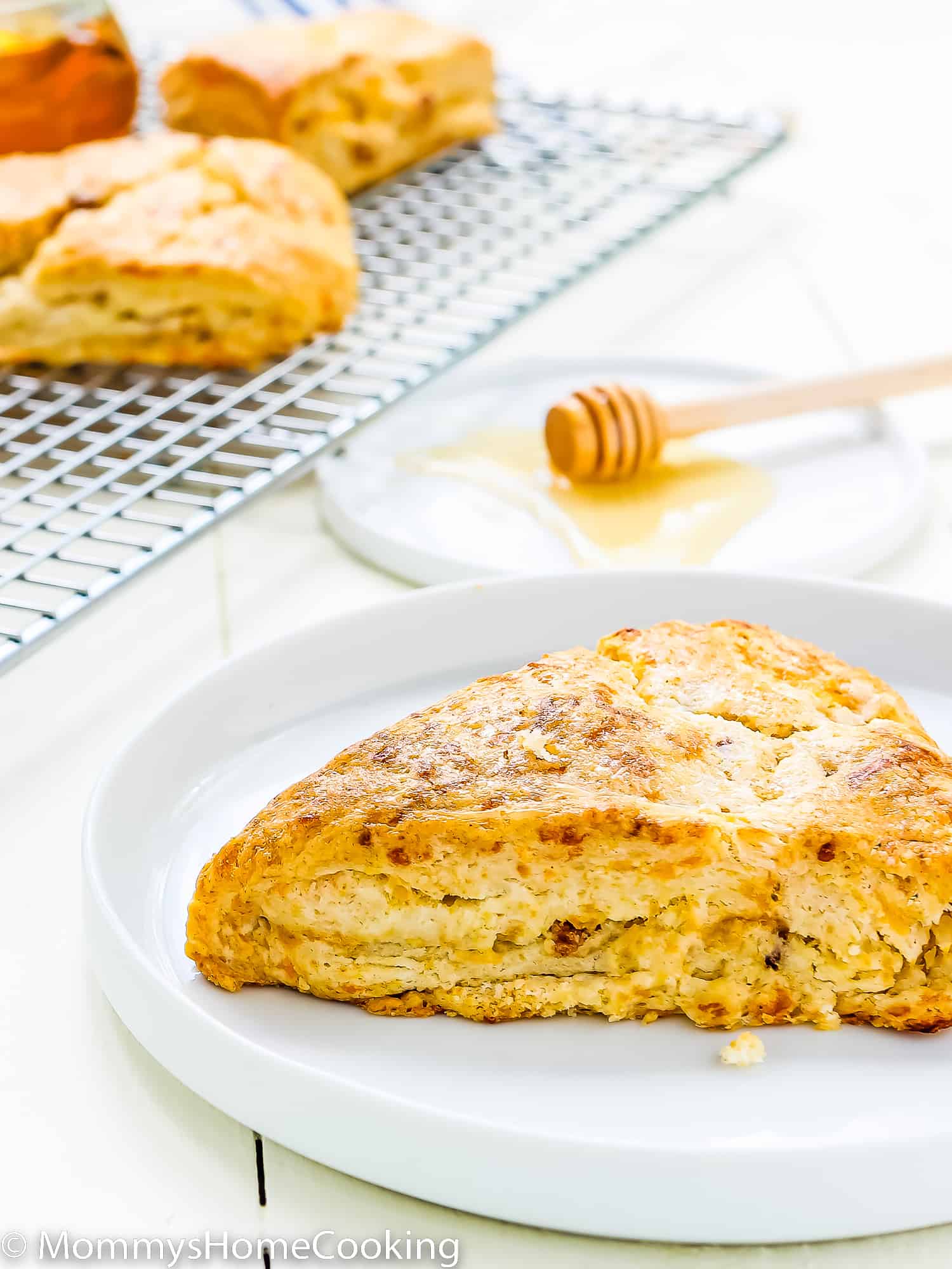an eggless Bacon Cheddar Scone on a plate with a cooling rack with more scones on the background.