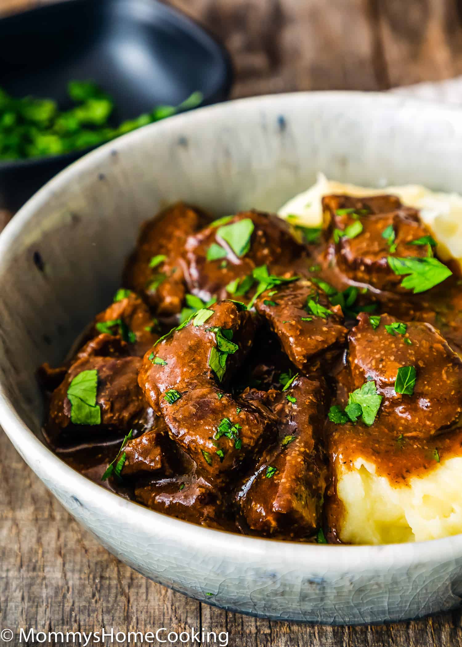 Easy Instant Pot Beef Tips with Gravy in a bowl with mashed potatoes and garnished with parsley.