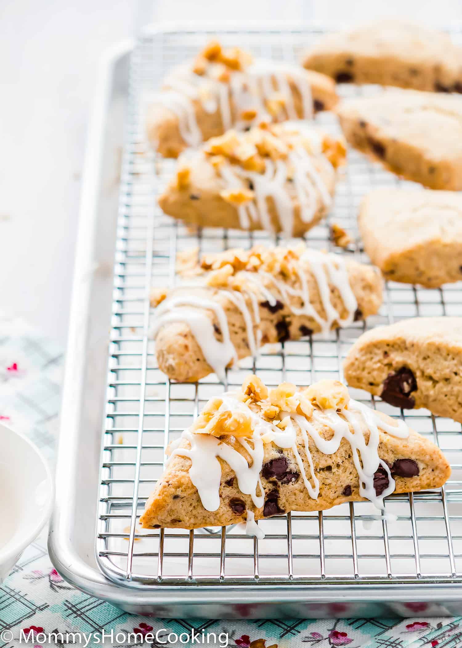 Eggless Chocolate Chip Scones with glaze and chopped nuts over a cooling rack.