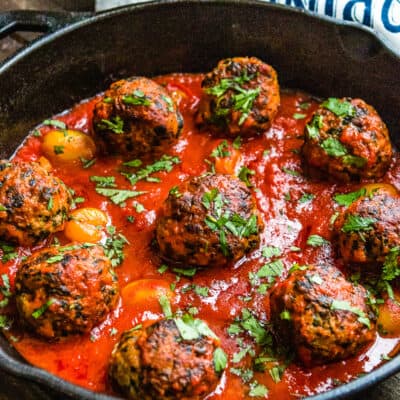 egg-free turkey meatballs with marinara sauce in a skillet and a tea towel in the background.