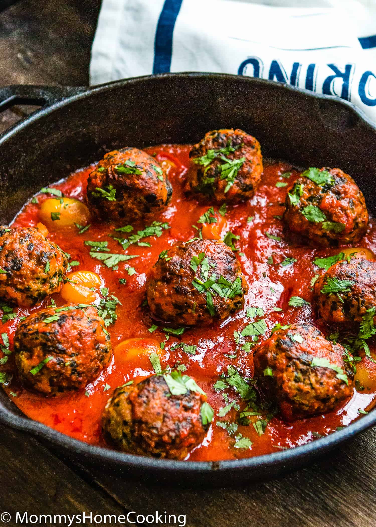 egg-free turkey meatballs with marinara sauce in a skillet and a tea towel in the background.