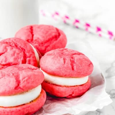 Eggless whoopie pies on a plate with a glass of milk in the background.