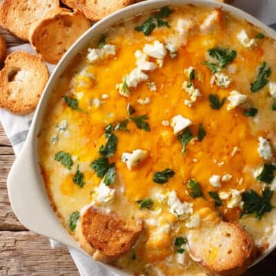 Super Bowl Buffalo Chicken Dip with blue cheese and greens close-up in a casserole dish