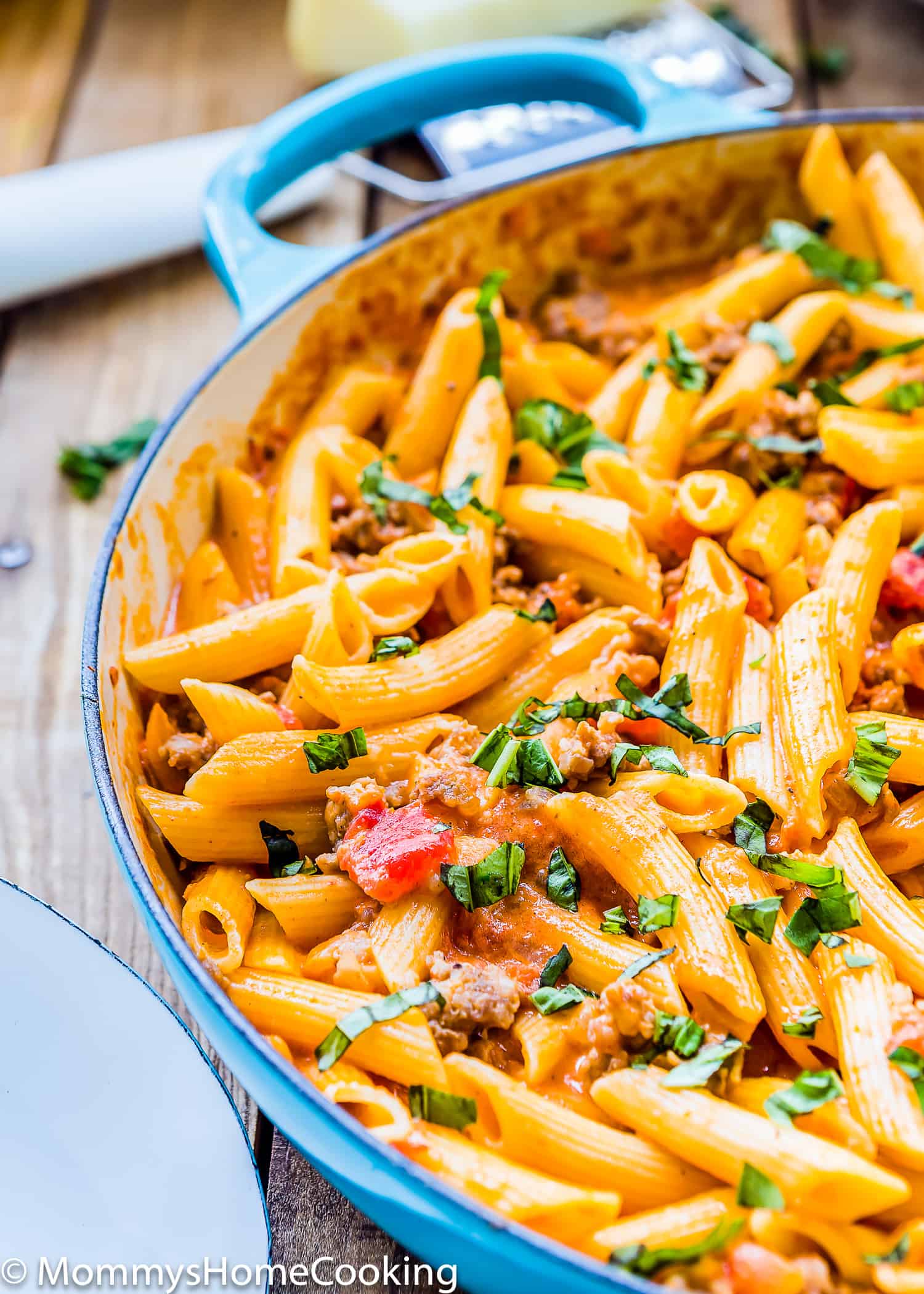 Creamy Sausage Pasta in a skillet garnished with chopped basil.
