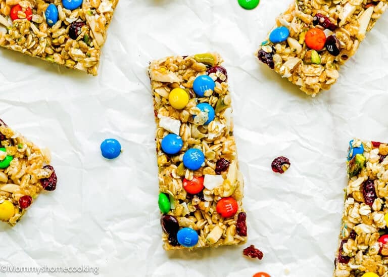 Easy No-Bake Protein Bars for Kids, these homemade granola bars blend oats, nuts, seeds, dried fruit, and candy-coated chocolates on crumpled white parchment paper for a fun and nutritious snack.