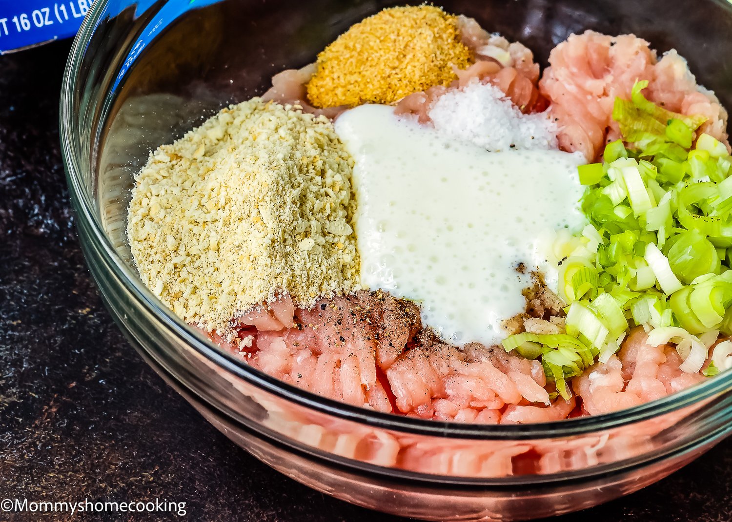 A bowl featuring Easy Teriyaki Turkey Meatballs mixed with ground meat, breadcrumbs, seasonings, chopped green onions, and a smooth white sauce. These egg-free delights offer a savory twist on a classic dish.