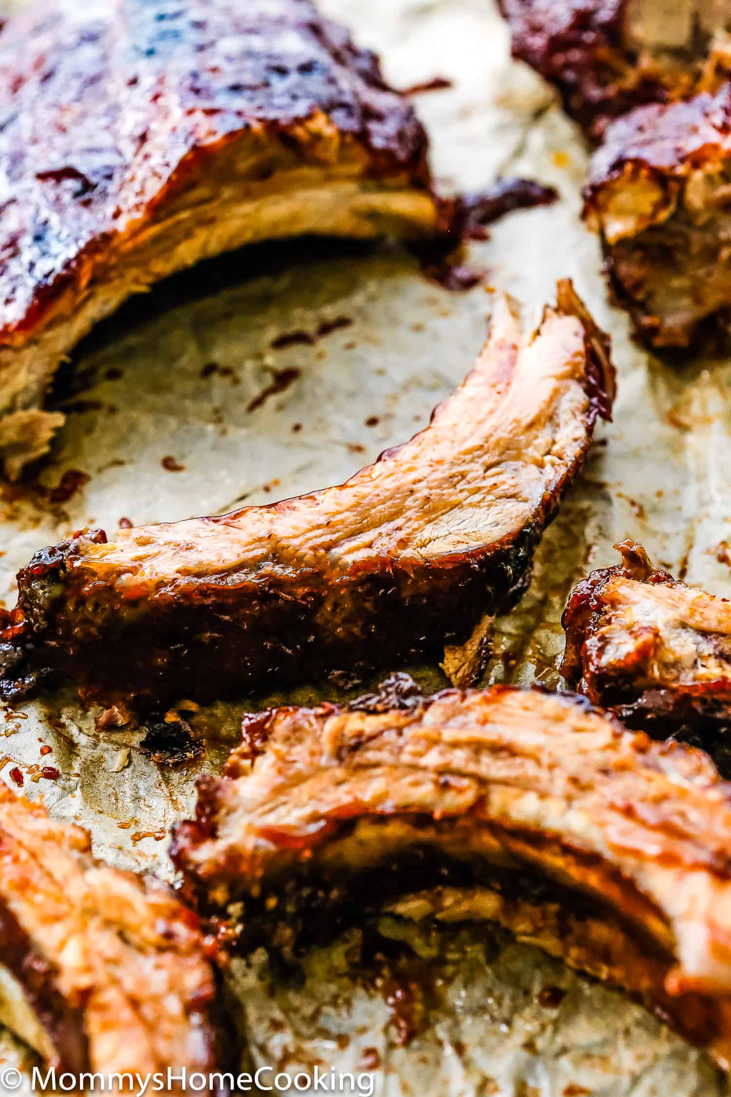 Fall-of-the-bone barbecue ribs over parchment paper.