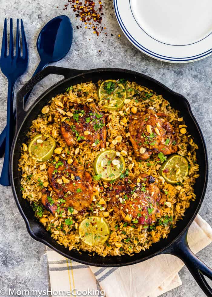 a cast iron skillet with Thai Chicken with Rice garnished with peanuts and chopped cilantro.