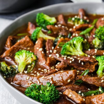 Beef and broccoli stir fry garnished with sesame seed in a serving bowl.