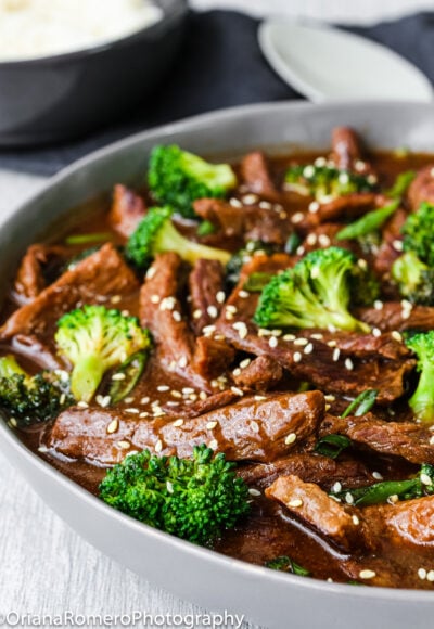 Beef and broccoli stir fry garnished with sesame seed in a serving bowl.