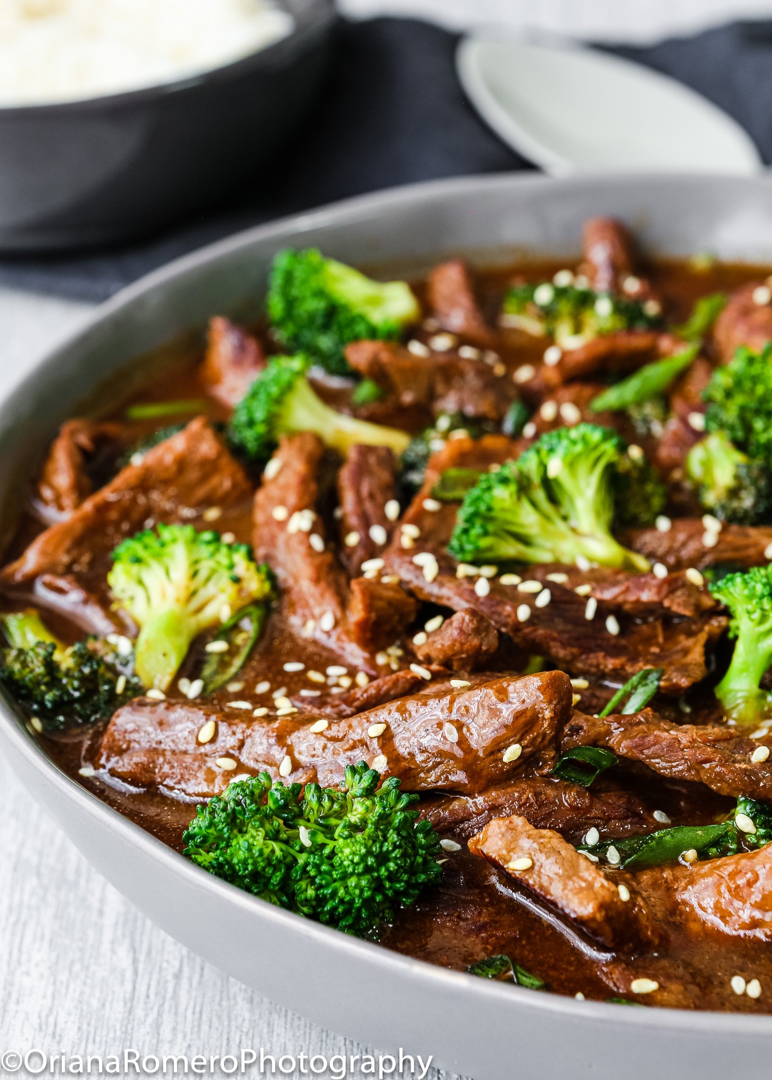 Beef and broccoli stir fry garnished with sesame seed in a serving bowl.