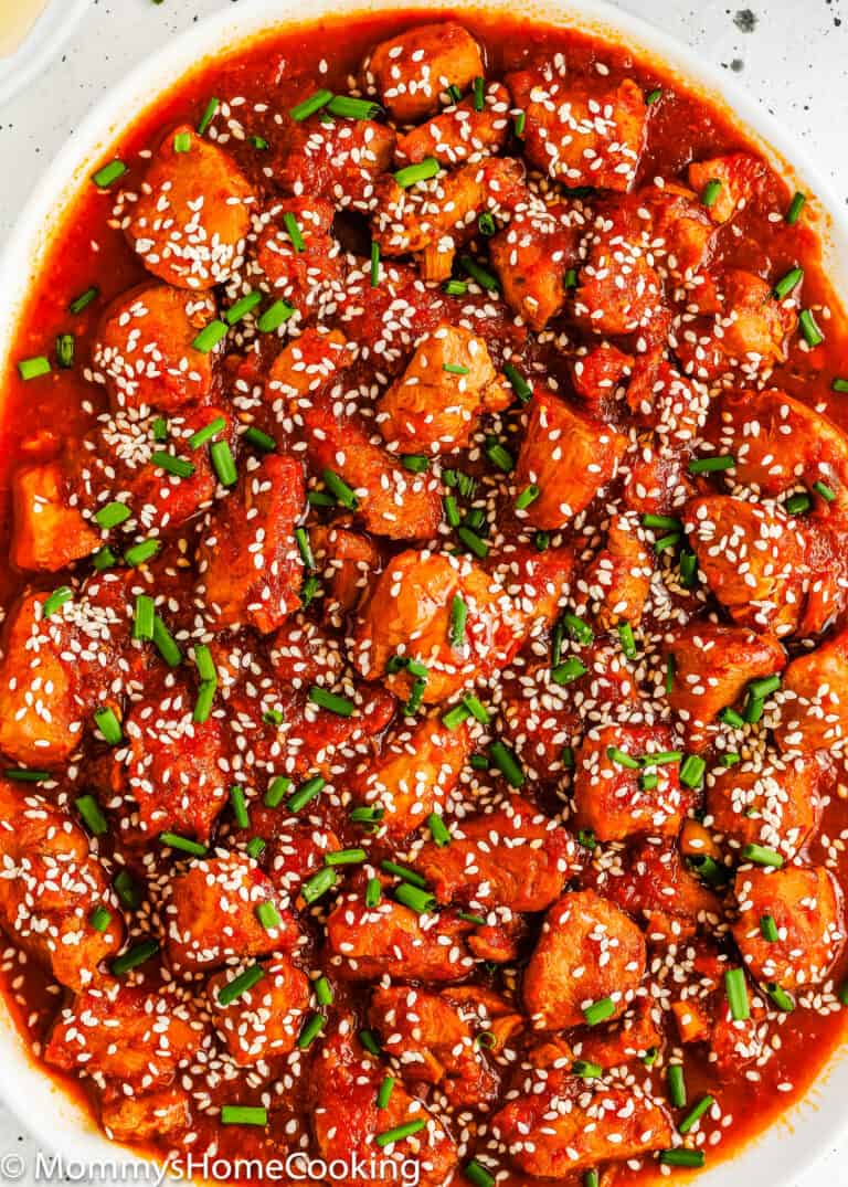 Korean Kimchi Chicken with sesame seeds and green onions on a plate.