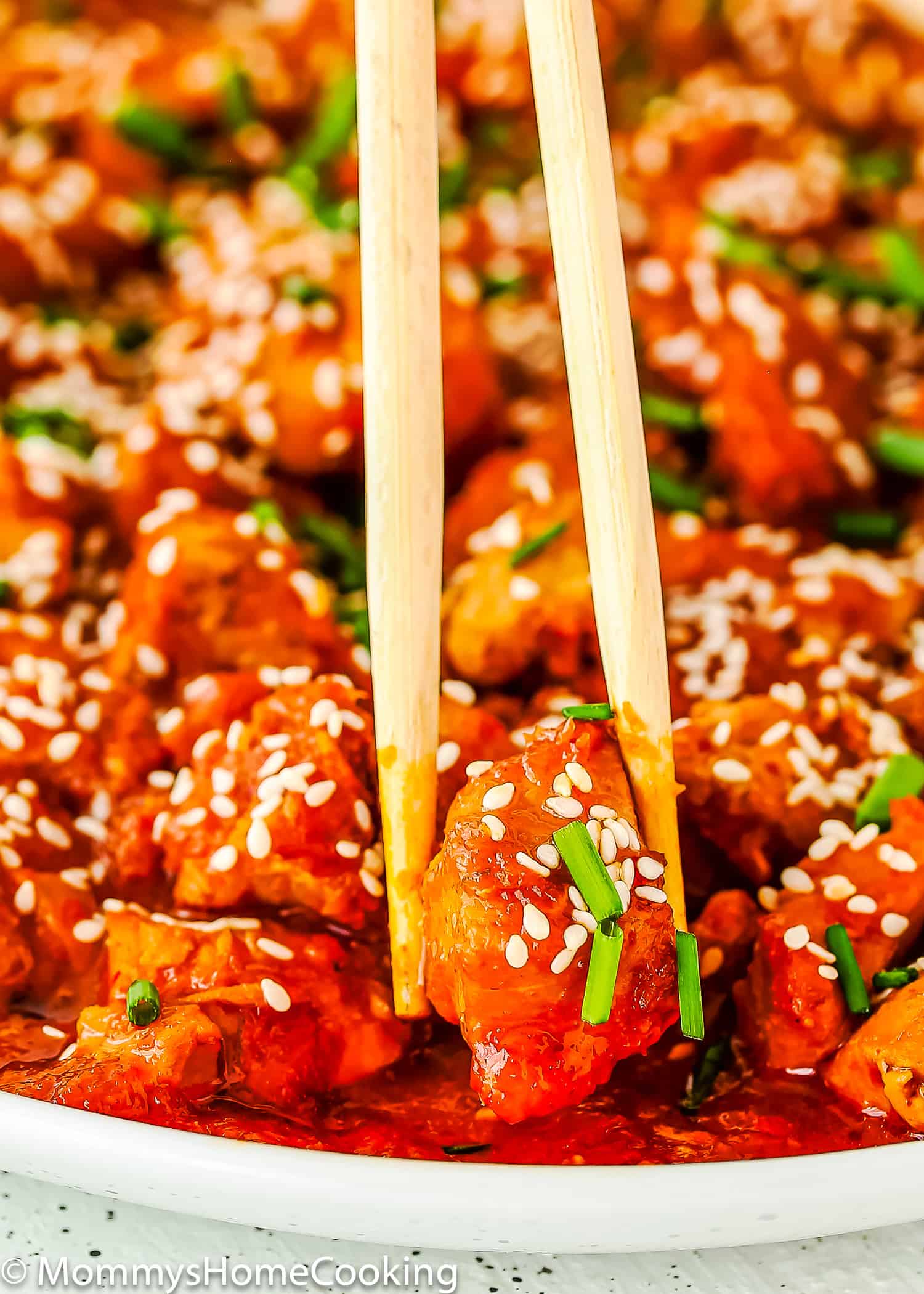 chopsticks holding a piece of Korean Kimchi Chicken.