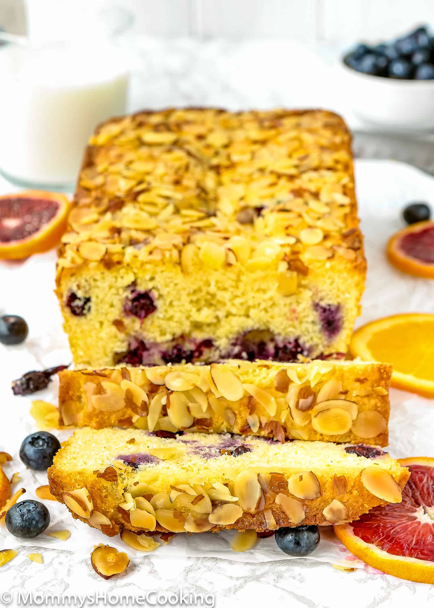 Eggless Orange Blueberry Cornbread Loaf sliced over a marble surface with fresh blueberries and orange slices.