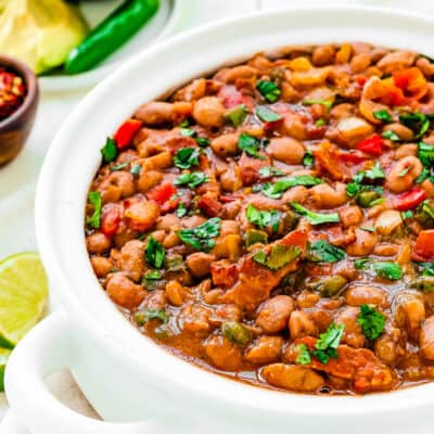 drunken bean (frijoles borrachos) in a white serving bowl garnished with chopped cilantro.