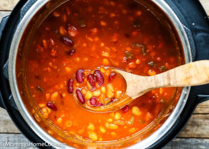 Homemade baked beans in a pot with a wooden serving spoon.