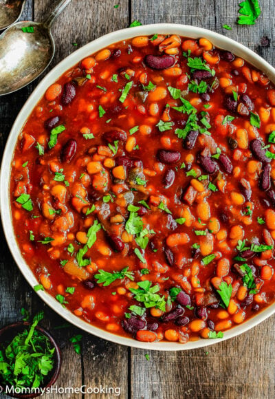 Homemade baked beans in a serving bowl garnished with chopped cilantro.