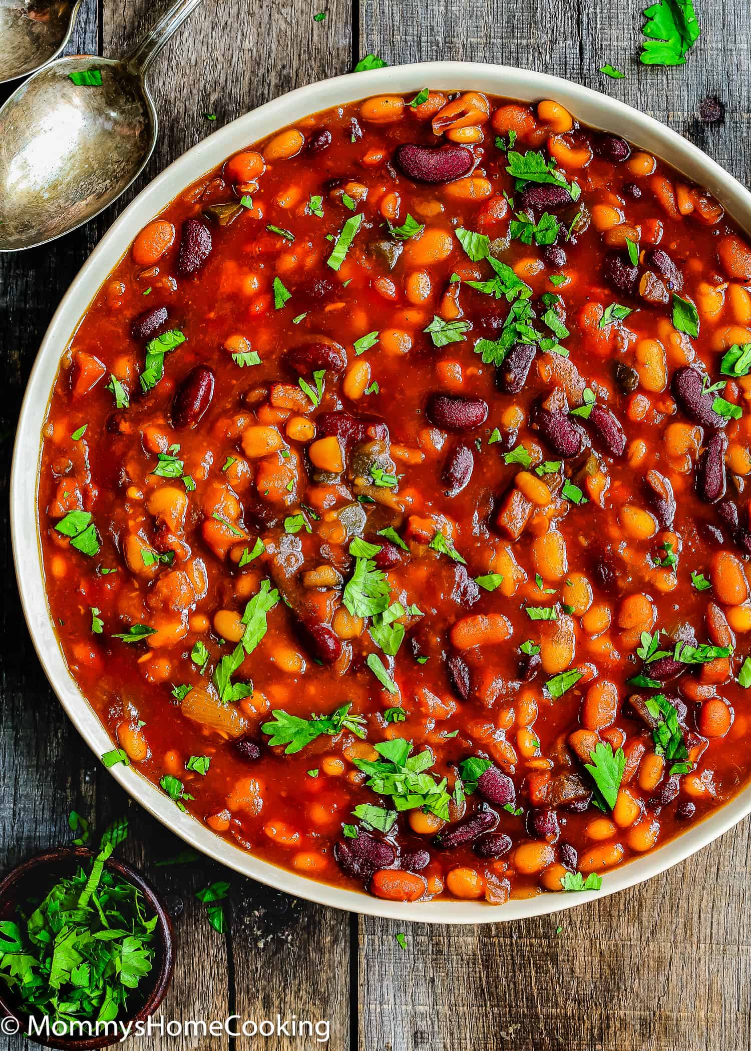 Homemade baked beans in a serving bowl garnished with chopped cilantro.