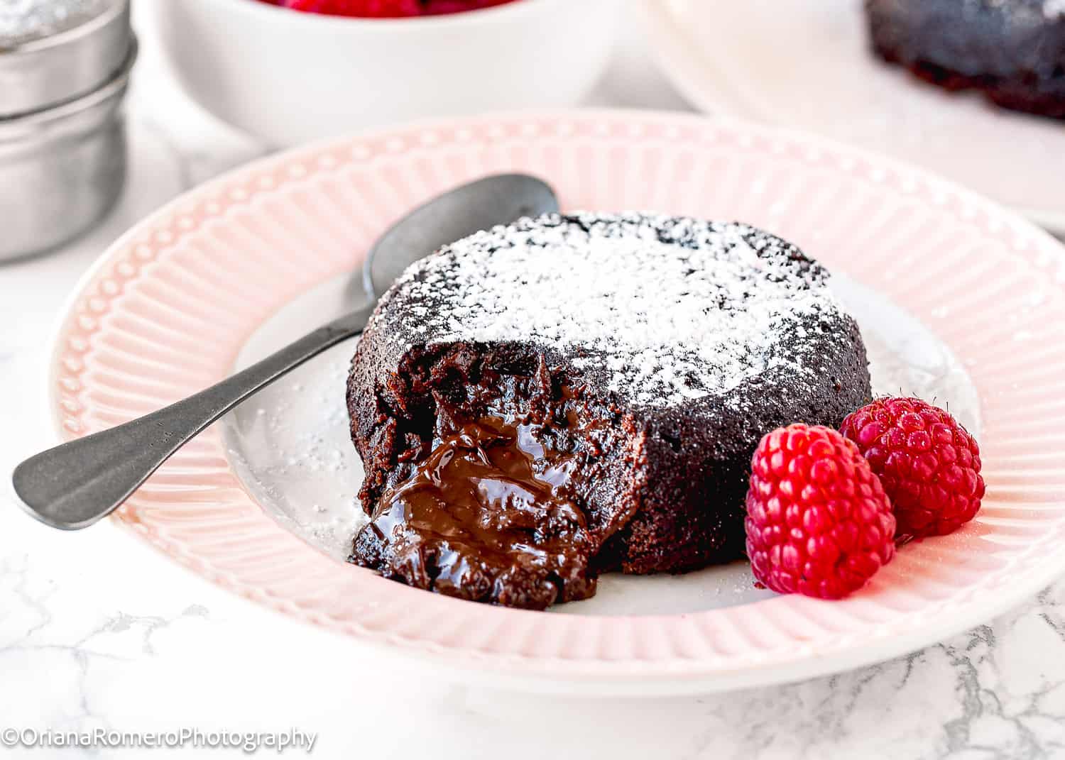 Eggless Lava Cake on a pink plate with fresh raspberries. 